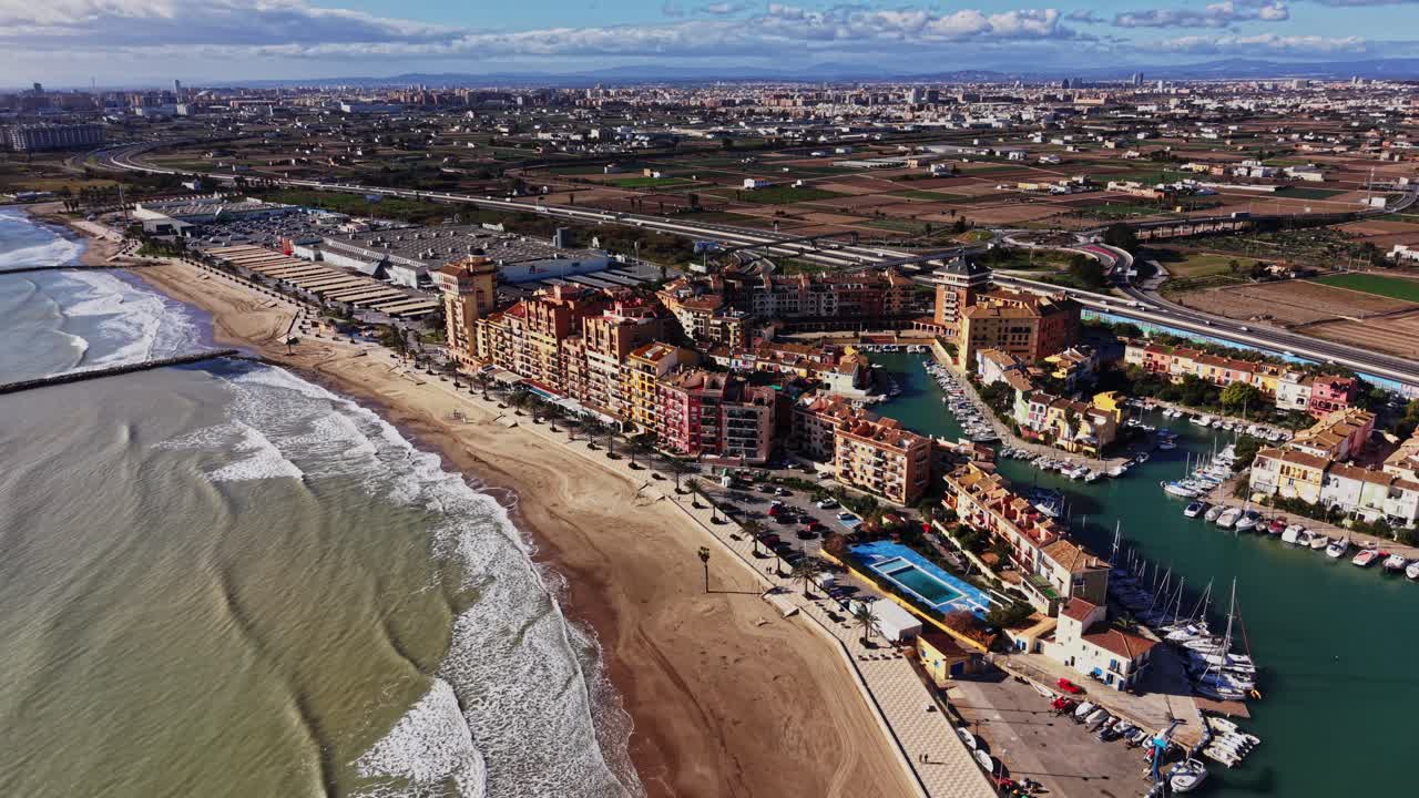 Kystudsigt over en strand og by i Spanien på en solskinsdag