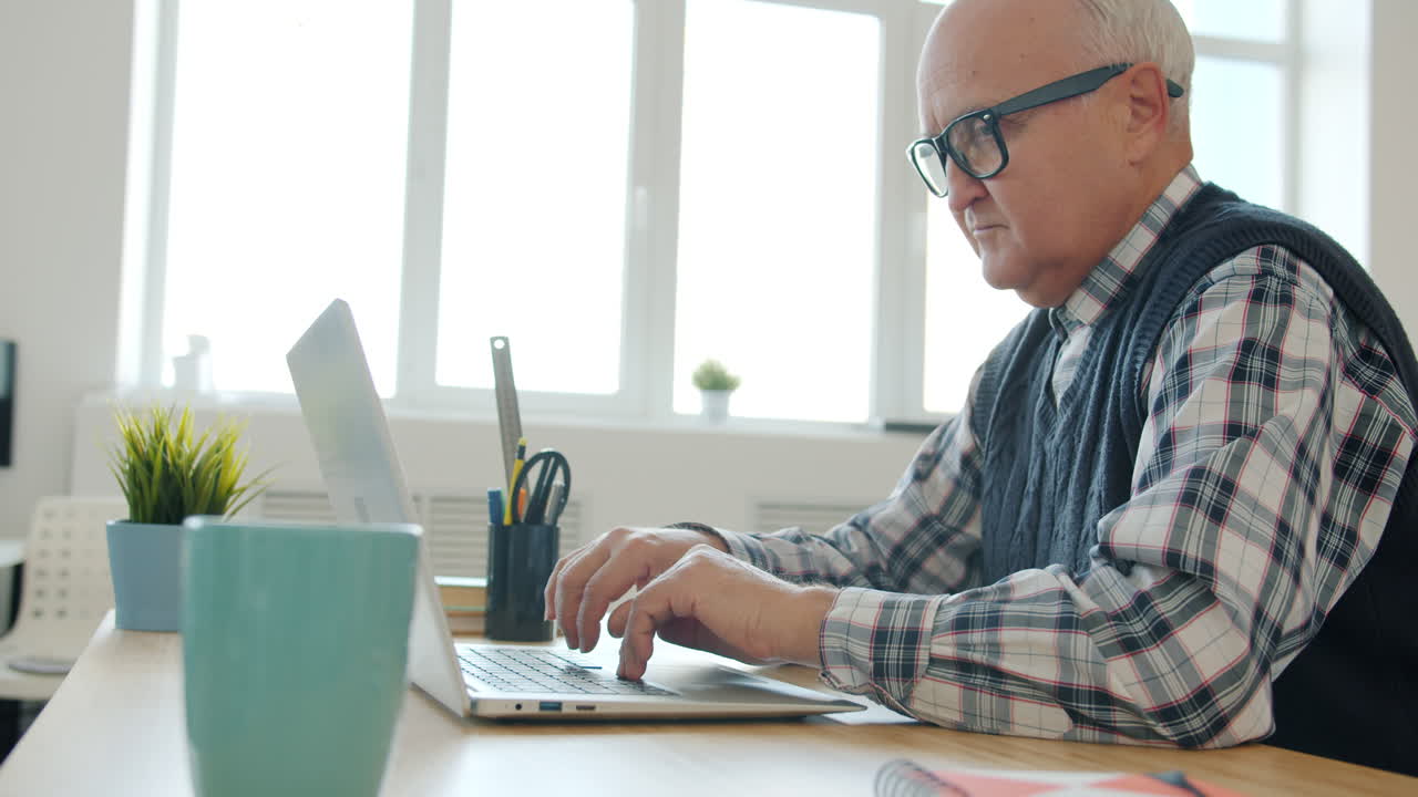 Older Man Working on Laptop in Home Office