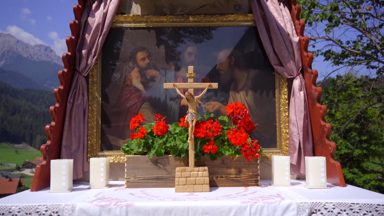 кадр с наклонной съемкой приближается к распятию на алтаре во время службы в католической церкви на открытом воздухе с горным пейзажем на заднем плане