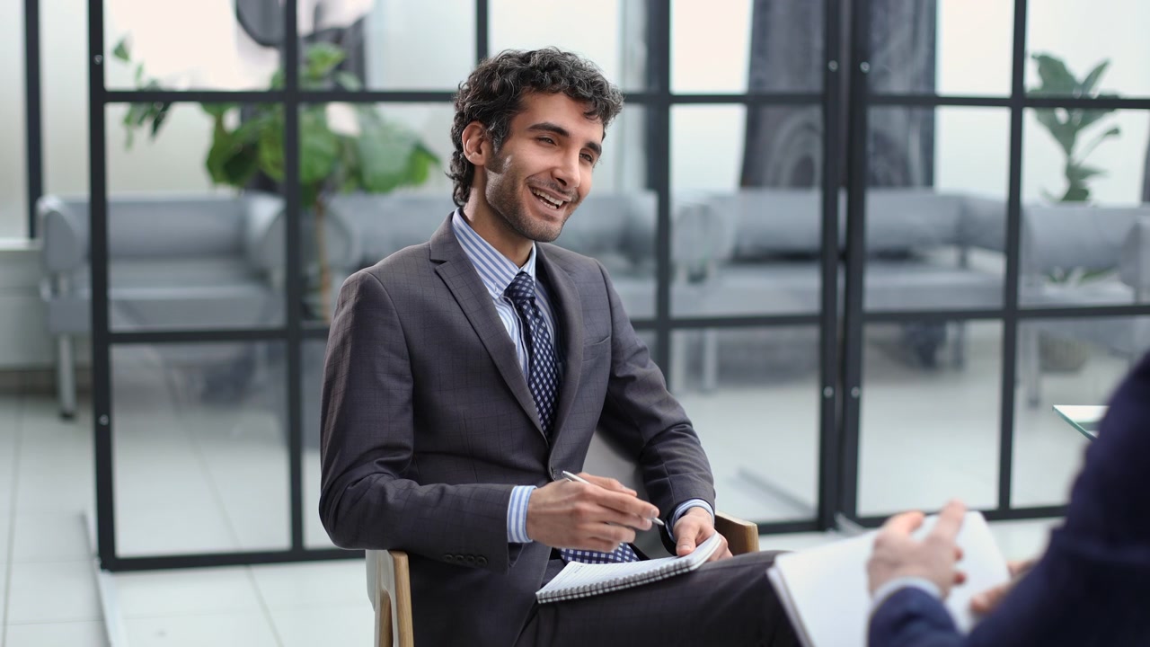 Young Businessman Smiling and Taking Notes During an Interview