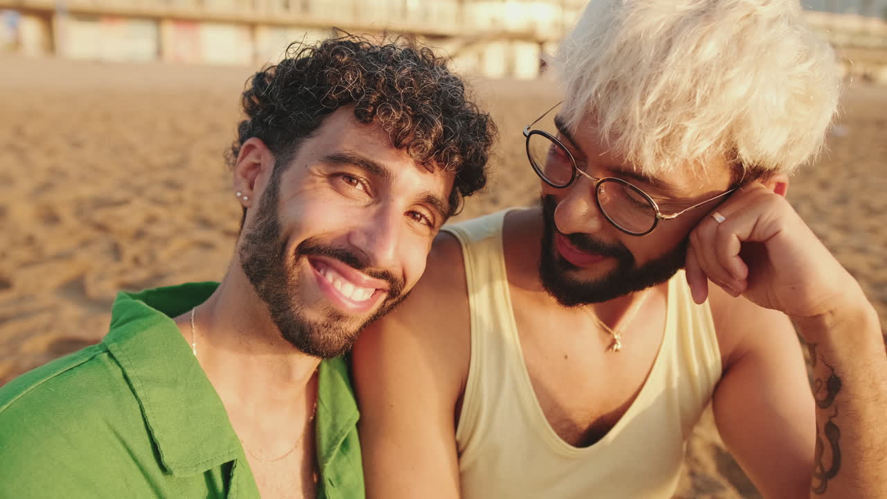 Coppia gay felice che sorride e si rilassa in spiaggia