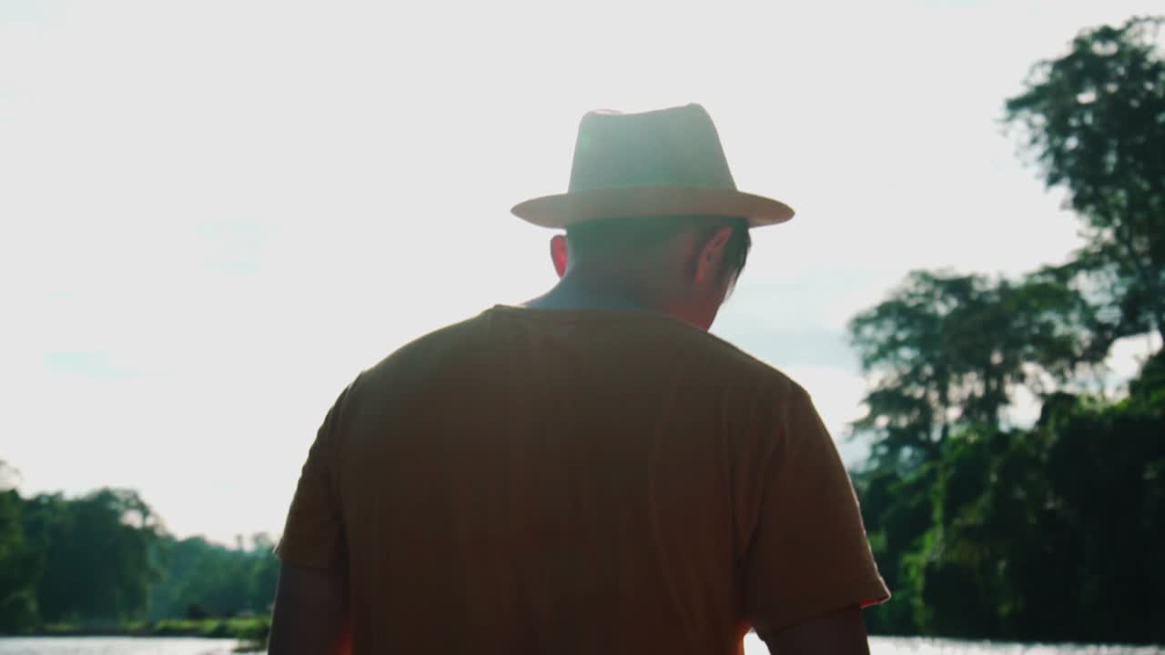 Silhouette of a young camper in the national park Brunei, walking near river, middle shot
