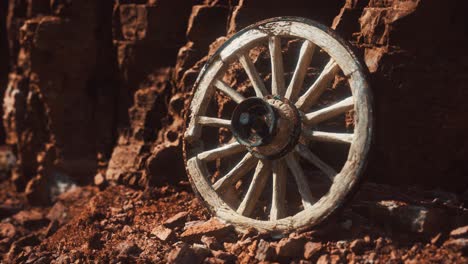 old wooden cart wheel on stone rocks