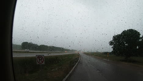 fuertes lluvias golpeando un gran parabrisas de un vehículo que estaba esperando la tormenta de lluvia en un área de descanso a lo largo de la interestatal