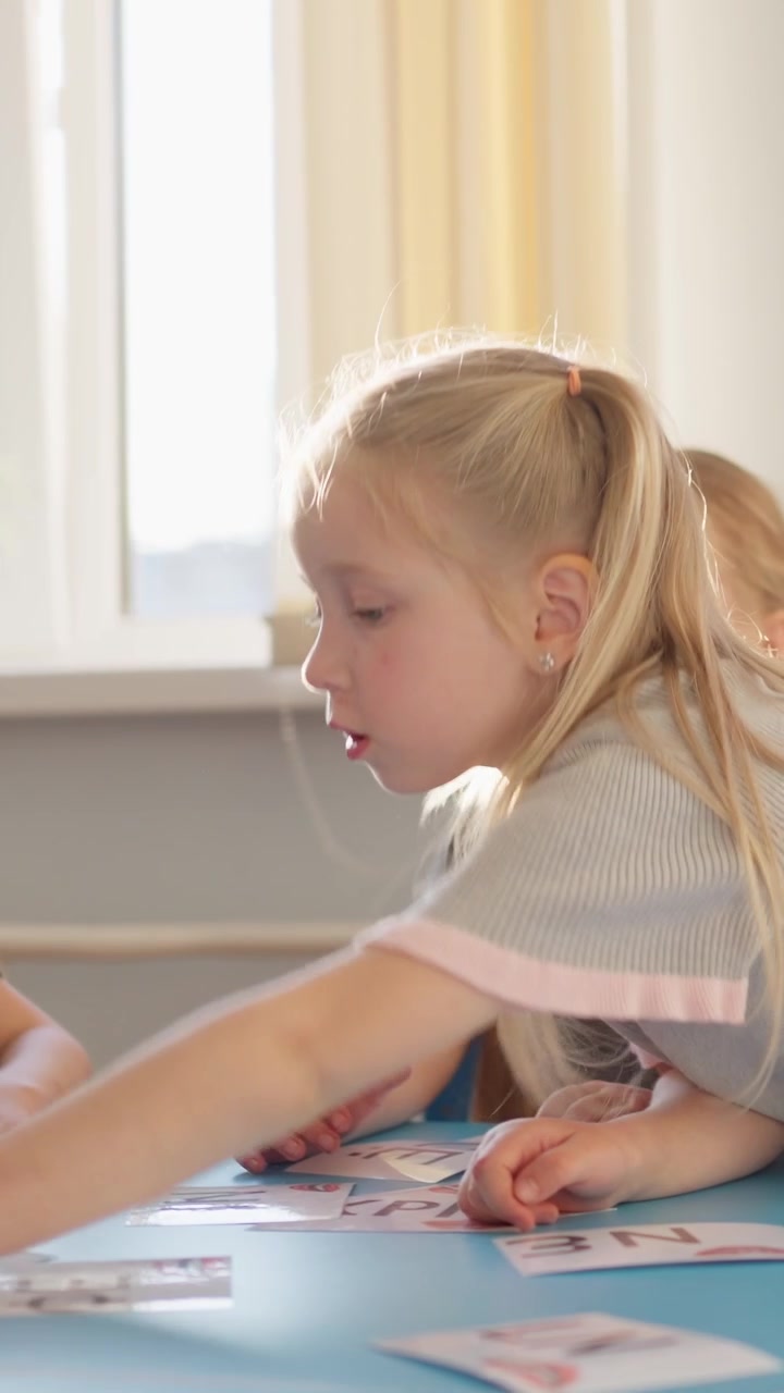 Due bambine imparano con carte educative a un tavolo.