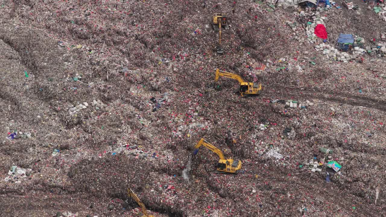 Escavatori che spostano tonnellate di rifiuti nella discarica di Bantar Gebang