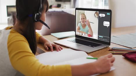 Asian-girl-doing-homework-and-having-a-video-call-with-classmate-on-laptop-at-home