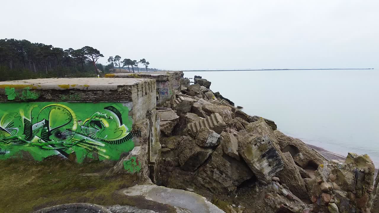 Aerial view of abandoned seaside fortification building at Karosta Northern Forts on the beach of Baltic sea in Liepaja in overcast spring day, establishing drone shot moving forward