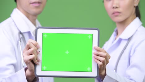 young asian couple doctors showing digital tablet together