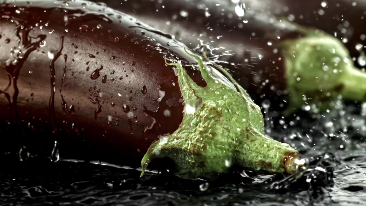 Vatten som stänker i slow motion på färsk lila aubergine