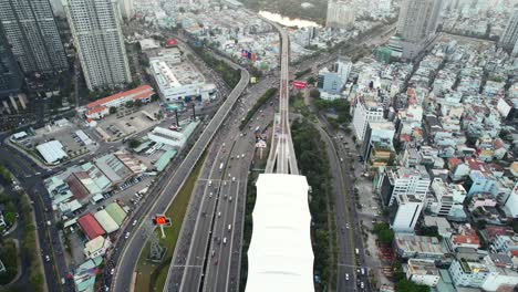 Luftaufnahme-Von-Oben-Nach-Unten-Von-Autos-Und-Motorrädern,-Die-Auf-Autobahnstraßen-In-Ho-Chi-Minh-Stadt,-Vietnam,-Bei-Sonnenuntergang-In-Der-Nähe-Einer-U-Bahn-Station-Fahren