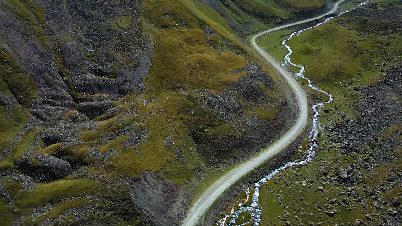 Winding Mountain Road Beside Stream in rocky Kyrgyzstan Valley, aerial