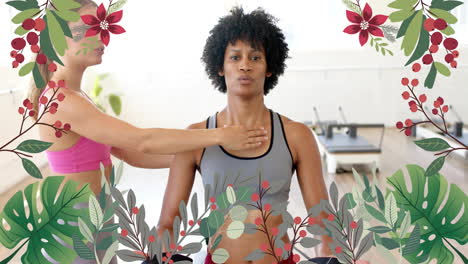 floral border animation over women practicing yoga in fitness studio