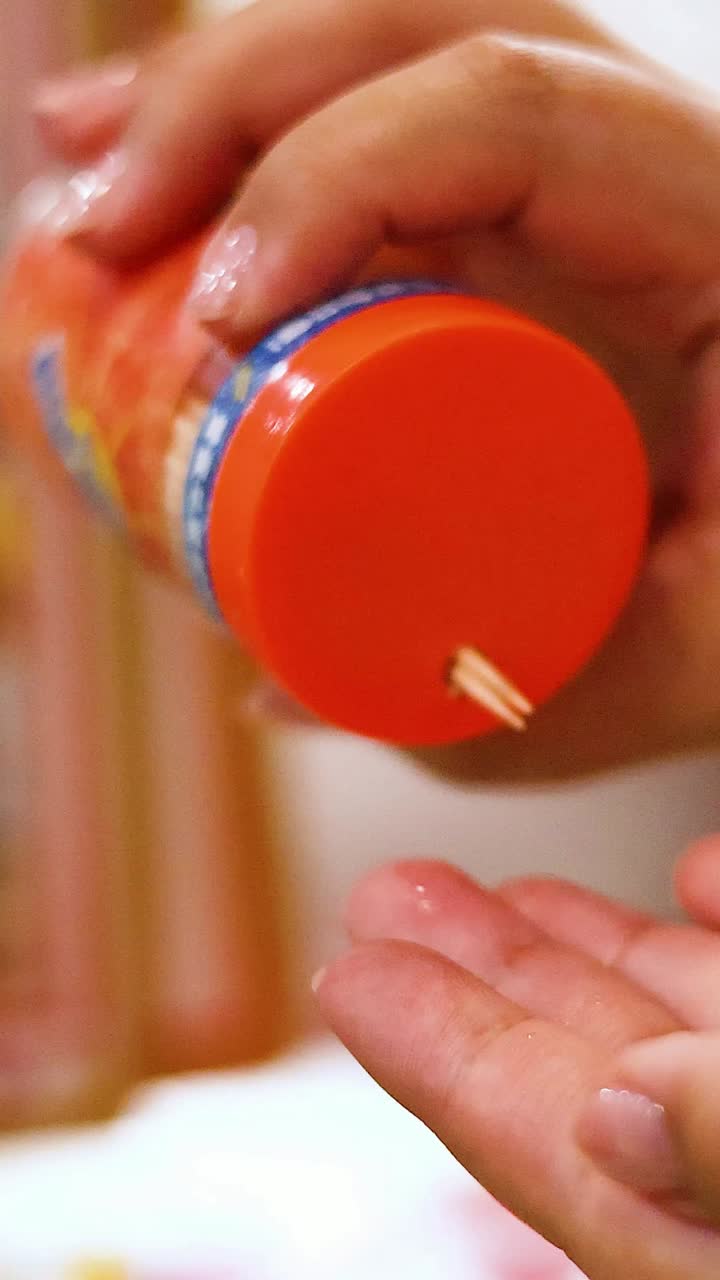 la mano vertiendo palillos de dientes al lado de una botella de refresco
