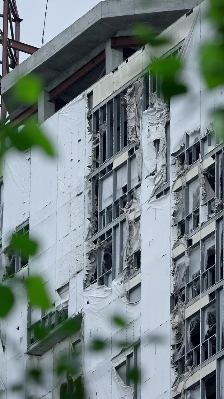 Edificio de gran altura sin terminar con láminas blancas rasgadas