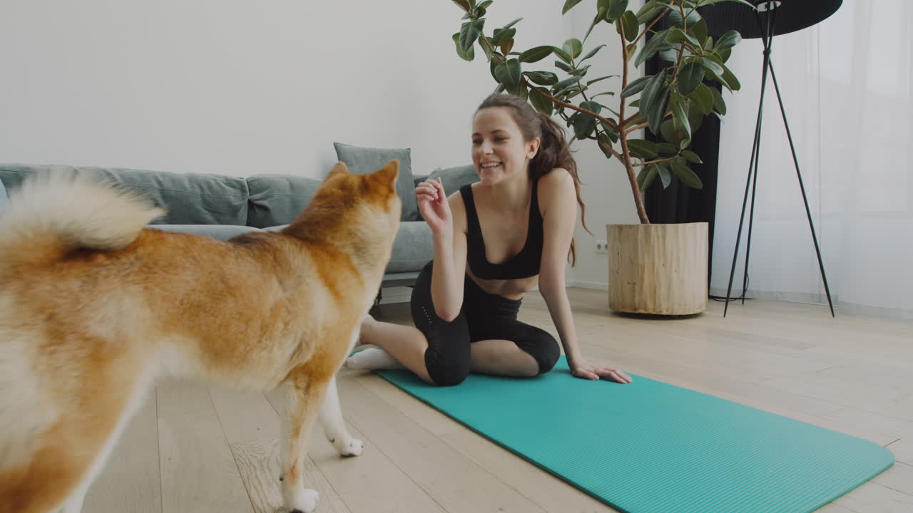 En pige tager en pause fra sin yogasession for at fodre sin søde hund