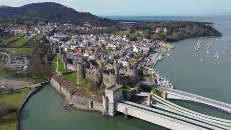 Eine-Luftaufnahme-Von-Conwy-Castle-An-Einem-Sonnigen-Tag,-Der-Auf-Das-Schloss-Zufliegt,-Mit-Der-Stadt-Im-Hintergrund,-Nordwales,-Großbritannien