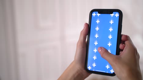 Woman slides, scrolls up and down blue chroma key screen in smartphone app.