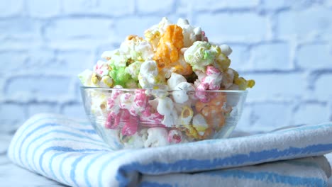 colorful popcorn in a glass bowl on a striped towel