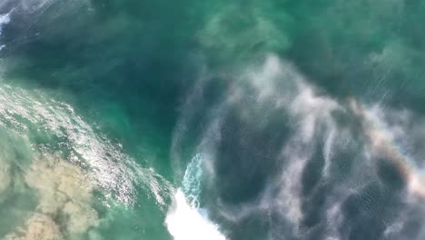 drone disparado desde arriba de la ola que pasa por dejar el arco iris en el spray