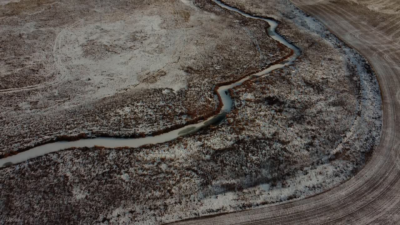 Flying over a frozen creek in the middle of a farmer's field in winter in Calgary