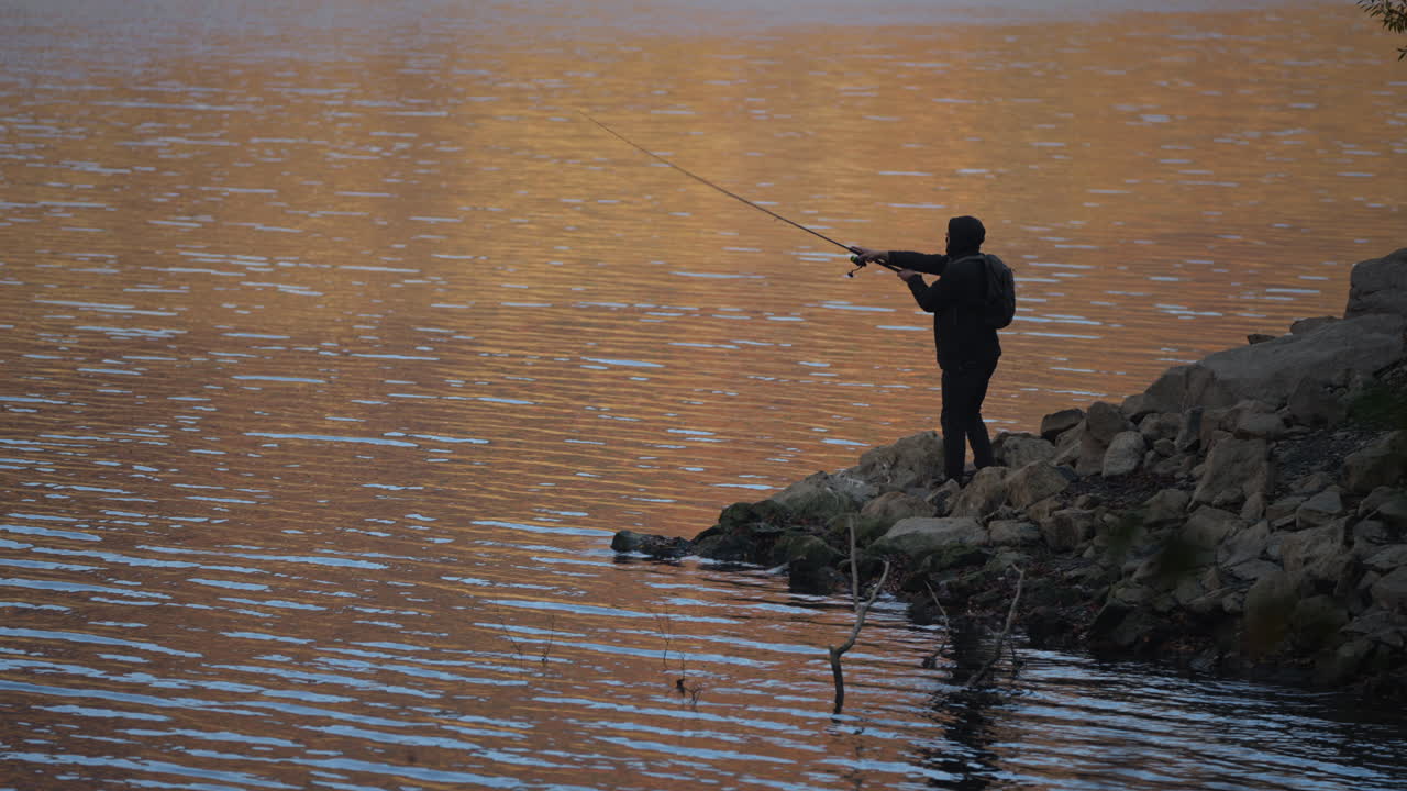 Pemancing saat Matahari Terbenam di Tepi Danau