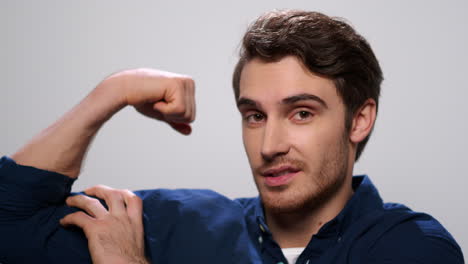 hombre fuerte mostrando bíceps en un fondo claro. tipo positivo posando en la cámara