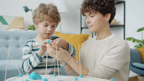 mother and child building a structure with playdough and sticks