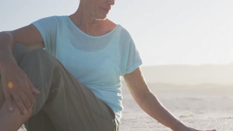 Senior-Caucasian-woman-enjoying-time-at-the-beach-with-sea-in-the-background