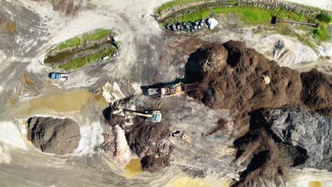 drone footage captures machinery processing soil and mulch in an open field under bright daylight