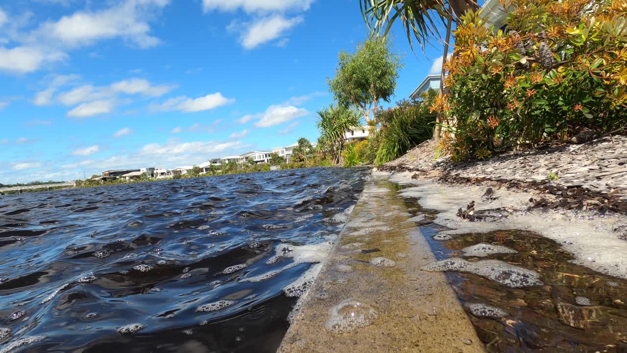 marea alta que sube sobre un canal frente al mar en un suburbio ajardinado en queensland