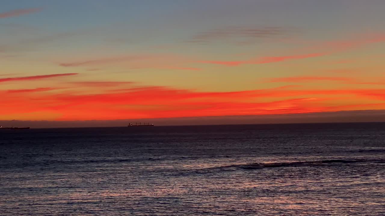 Dramatic orange sky over ocean with some clouds in the middle