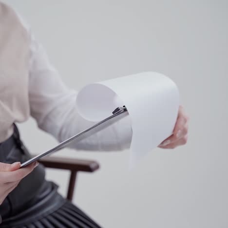 folder with papers in woman's hands. businesswoman in white blouse sitting in the chair and reading. close-up. slow motion.
