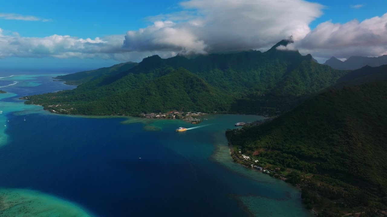 Luftdroneoptagelse af Sydlige Stillehav, Moorea og Bora Bora, med et krydstogtskib i Opunohu-bugten og en offentlig strand i Fransk Polynesien. En koralrevskanal passeres på en solrig morgen med blå himmel og skyer over en turkis lagune, med en baglæns panorering opad.