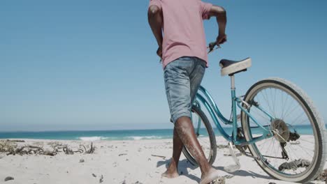 senior couple walking with a bike at the beach