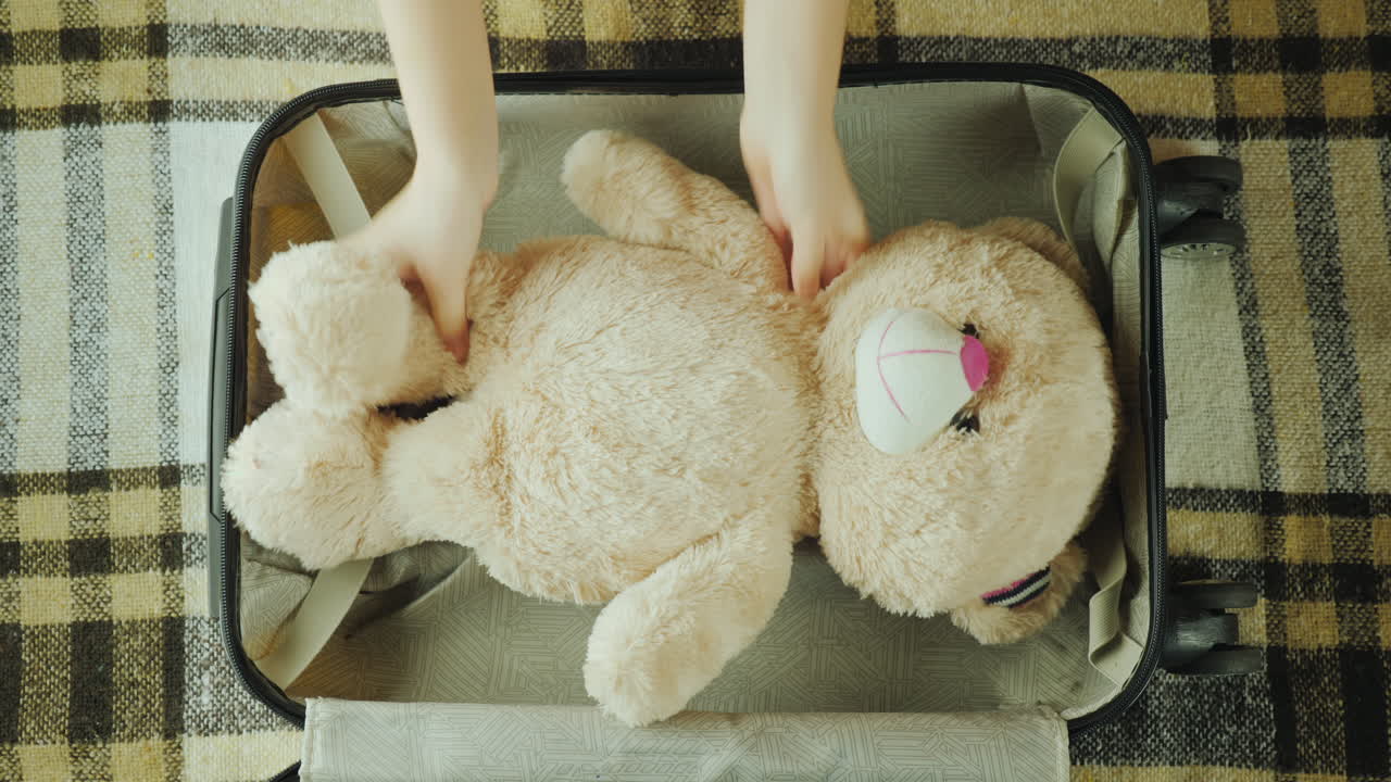 그 아이는 어린이 개념 4k 비디오와 함께 여행하는 여행 가방에 장난감을 넣습니다.