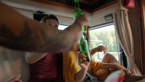 group of young friends spending time inside the camper on drinking beer and relaxing.