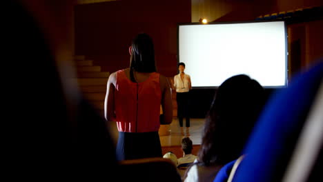 joven empresaria haciendo preguntas a una oradora asiática durante un seminario en el auditorio 4k