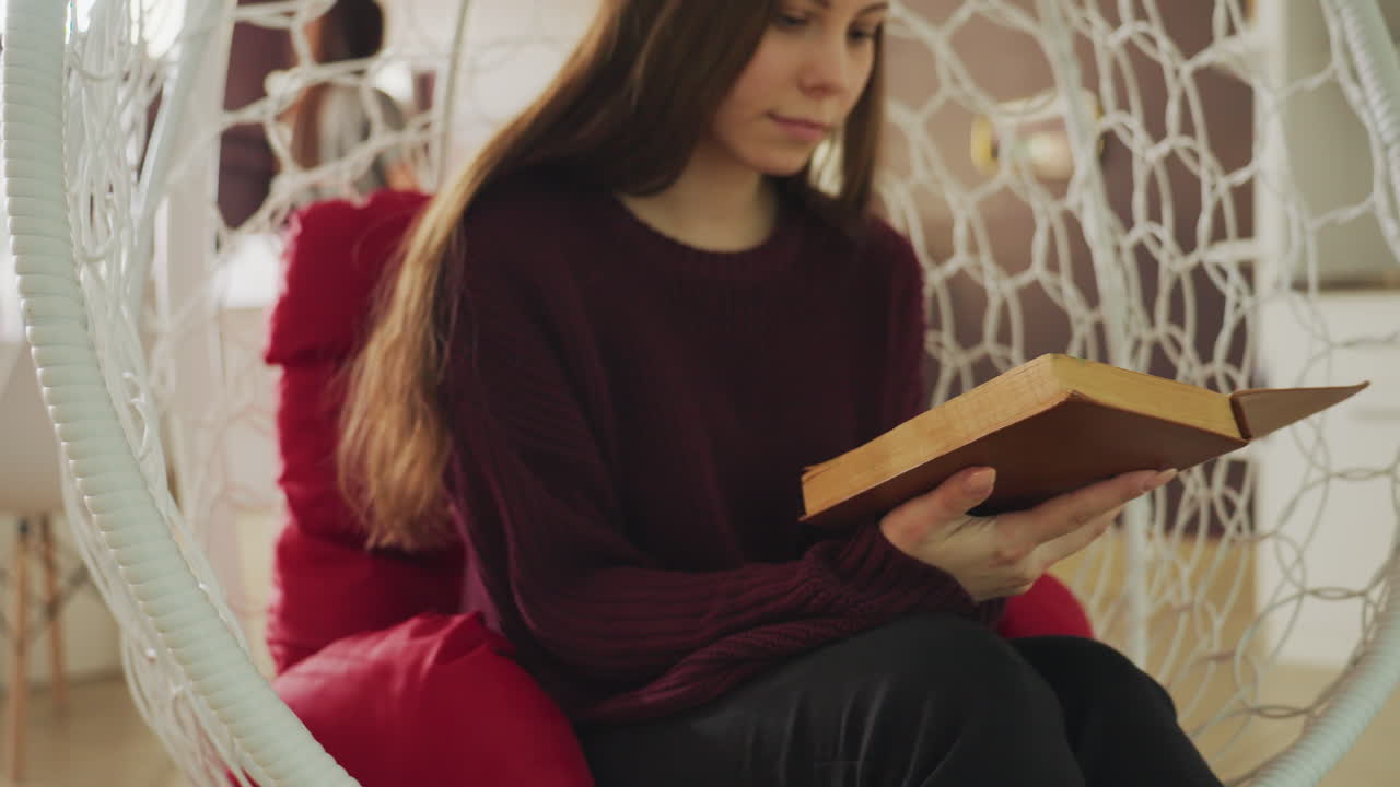 Una mujer lee plácidamente, una dama amable explora literatura vintage en silencio, una mujer sentada participa con elegancia en la lectura de un libro antiguo de la biblioteca, disfrutando tranquilamente de una novela clásica en un acogedor entorno de biblioteca doméstica