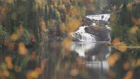 una cascada en el bosque de otoño reflejada en las aguas tranquilas del lago