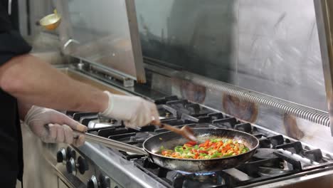 chef frying green brussels sprouts, cabbage in pan with flambe technique close-up