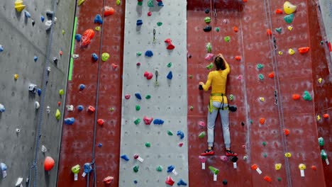 Woman-practicing-rock-climbing-in-fitness-studio-4k