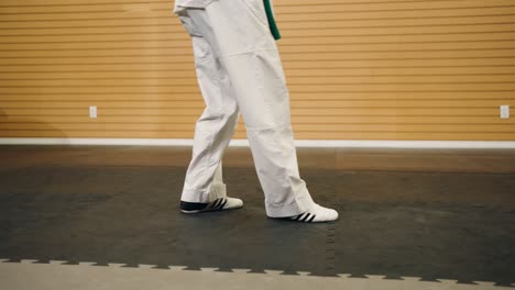 A-Martial-Arts-Black-Belt-Kung-Fu-Karate-Taekwondo-Master-Does-Back-and-Forth-Combat-Footwork-Inside-a-Gym-Training-Studio-While-Wearing-a-White-Gi-Dobok-Outfit