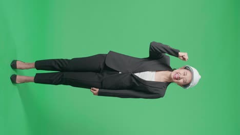 full body of happy asian female engineer with safety helmet celebrating while standing on green screen in the studio