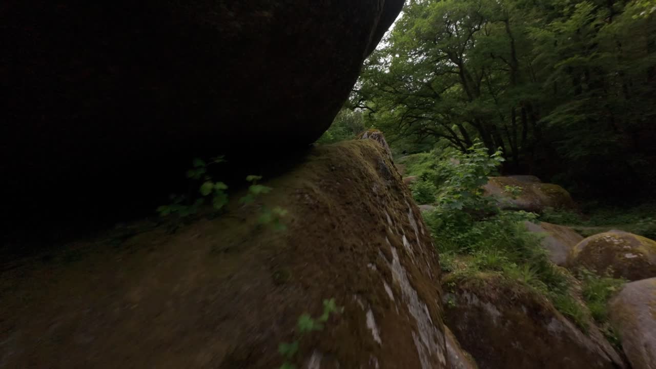 Drone footage of an FPV flight through foliage and rock formations of Huelgoat Forest