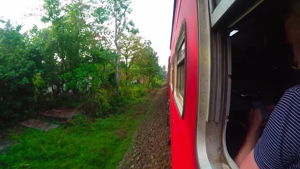 A guy writing on a mobile phone while travelling on a train in Sri Lanka.