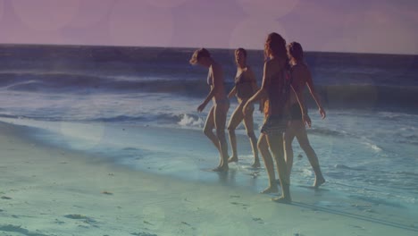 animation of glowing lights over group of diverse female friends by the sea