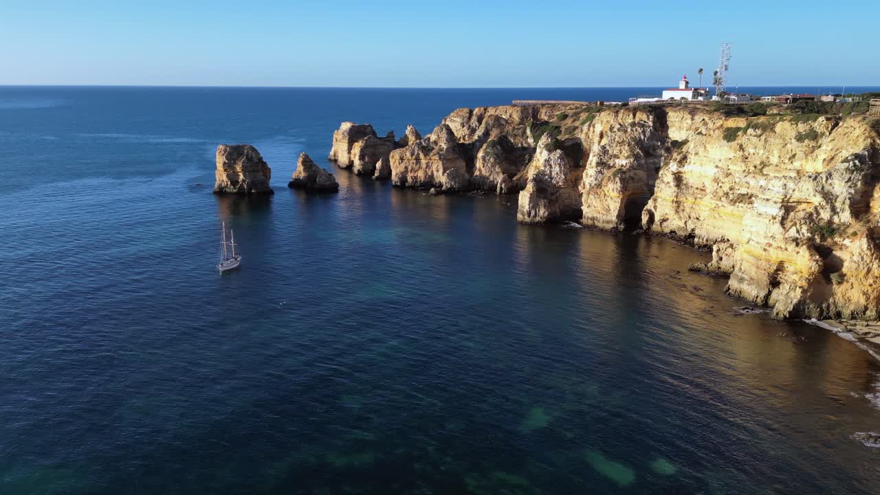 Stunning Aerial View of Algarve Coastline with Sailboat and Lighthouse