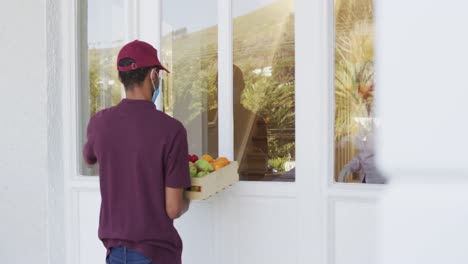 delivery man delivering groceries to senior woman wearing face mask at home