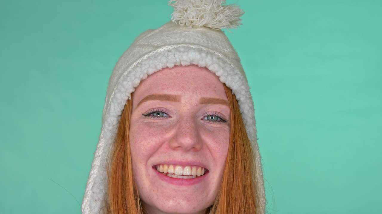 mujer pelirroja sonriente con ojos azules y gorro de invierno cálido en la cabeza